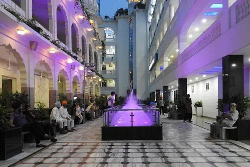 A courtyard with a fountain, seating areas, and a tiled floor. 2