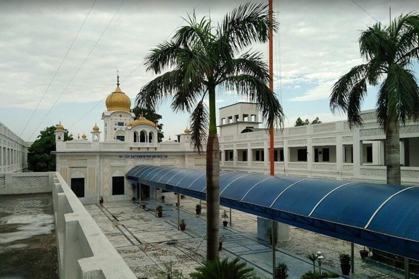 A covered walkway, palm trees, and a building with a golden dome. 1