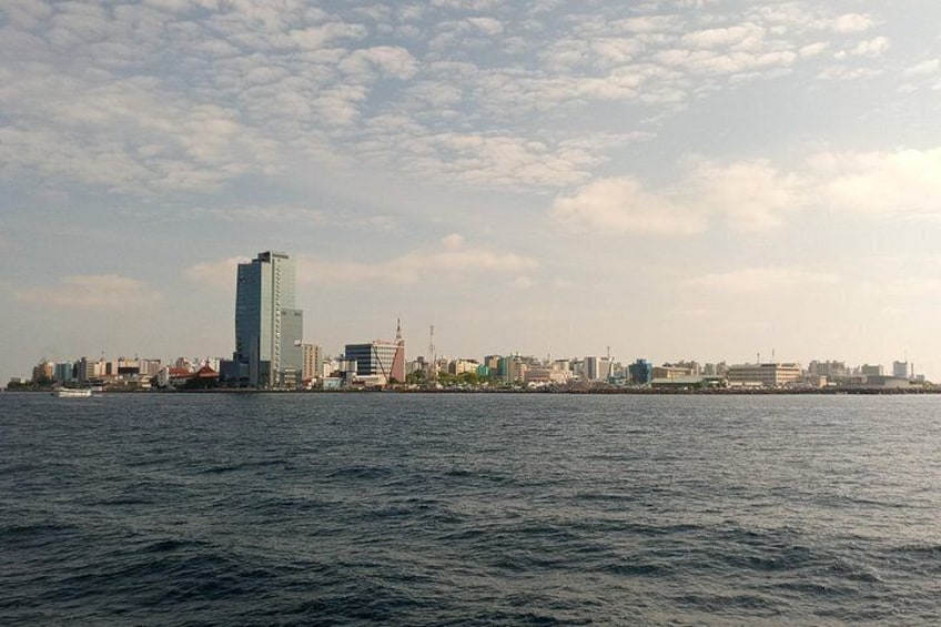 Un paisaje urbano costero con un rascacielos destacado, un puente y un mar tranquilo. 4