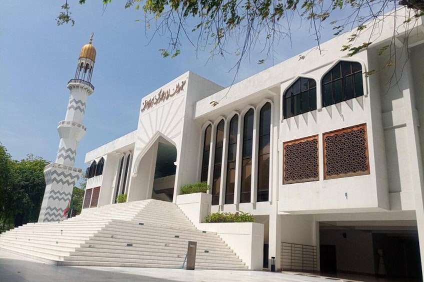 A mosque with a minaret, arched windows, and a staircase leading to the entrance. 2