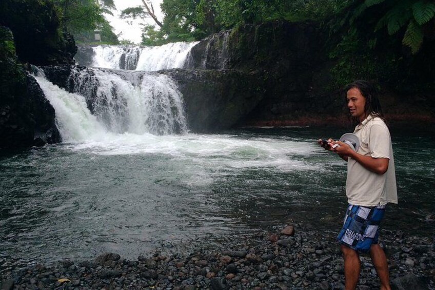 A waterfall, rocky riverbed, and a person standing by the water. 3