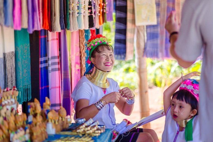 A person wearing a colorful headdress and jewelry, sitting at a table with various items. 5