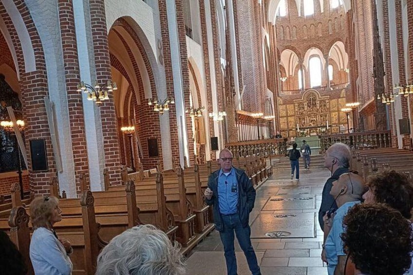 Interior de una iglesia con altos techos abovedados, bancos de madera y un pasillo central que conduce a un altar. 2