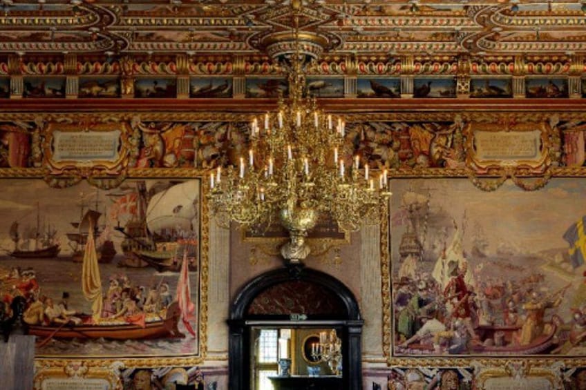 An ornate interior with a large chandelier, detailed murals, and classical architecture. 2