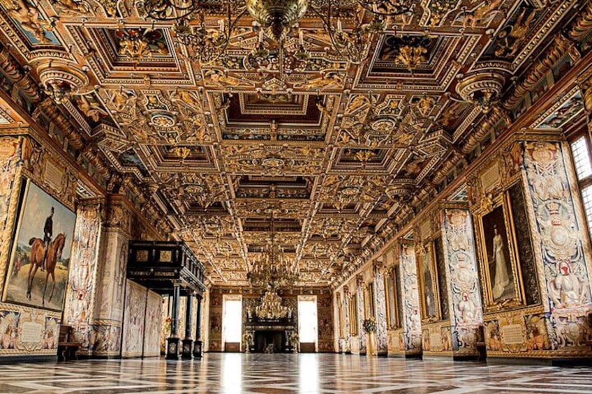 Una sala decorata con elaborate decorazioni al soffitto, colonne di marmo e pavimento a scacchi. 2