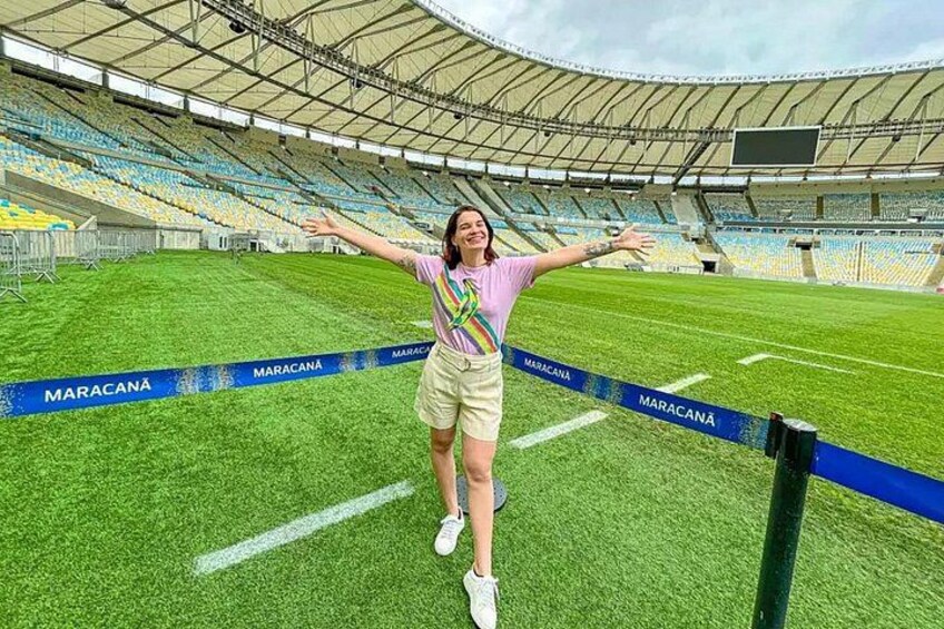 A person standing on a football pitch with a stadium in the background. 4