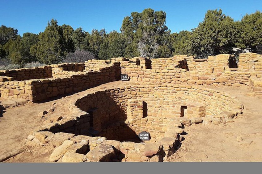 Ancient stone ruins with a circular structure and a sign indicating a historical site. 4