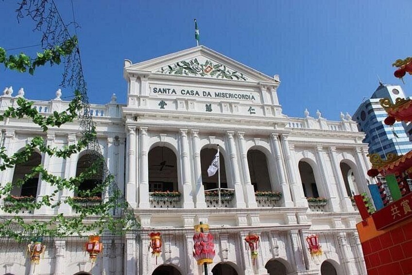 Un bâtiment de style colonial, peint en blanc, doté de fenêtres en arc de cercle et d’une enseigne indiquant « Santa Casa da Misericórdia ». 5