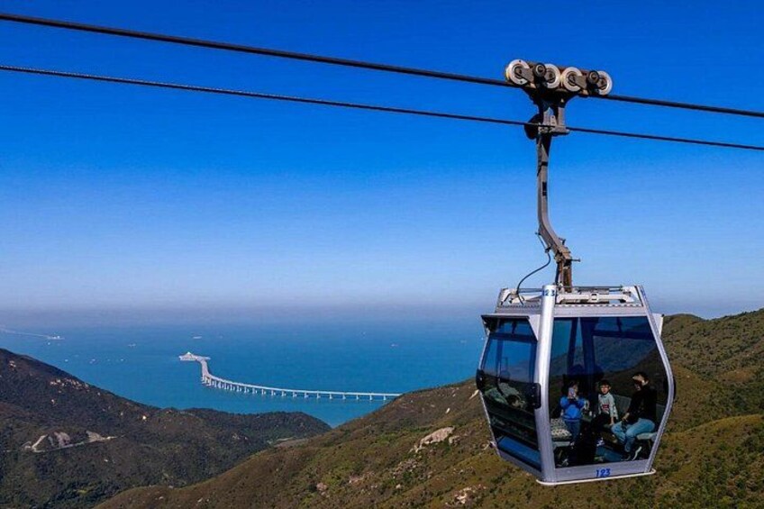 A cable car suspended over a mountainous landscape with a bridge in the distance. 4