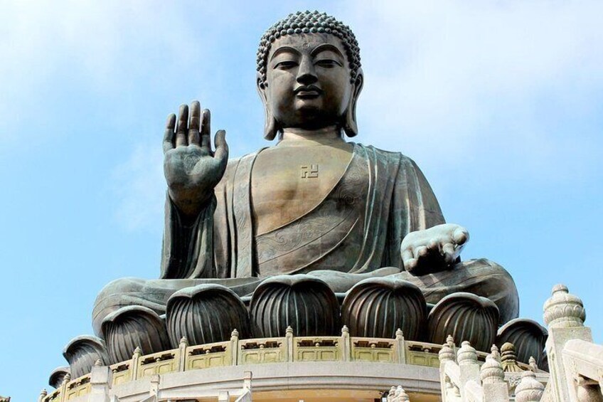 Una gran estatua de Buda con una mano levantada, rodeada de arquitectura ornamentada. 1