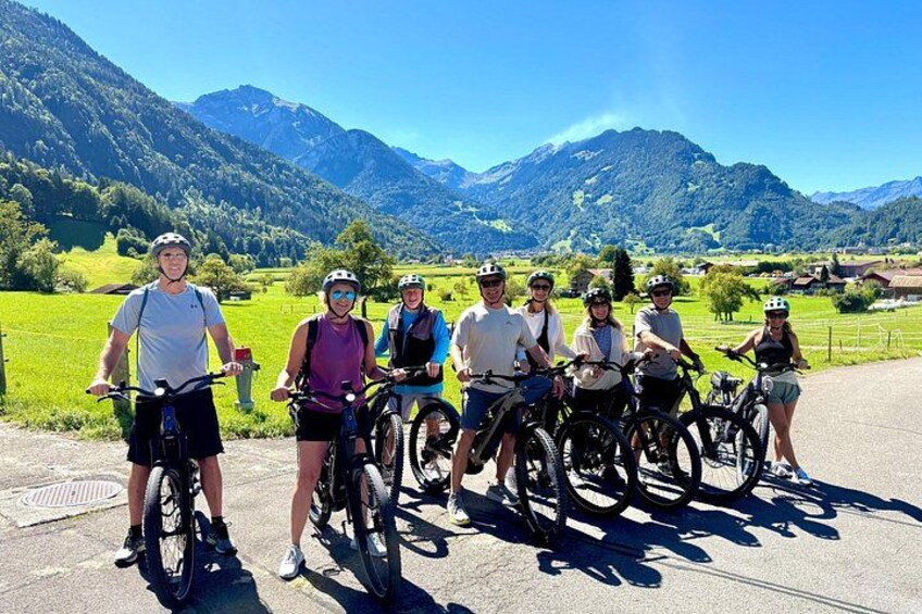 A group of cyclists on a road with a mountainous landscape in the background. 1