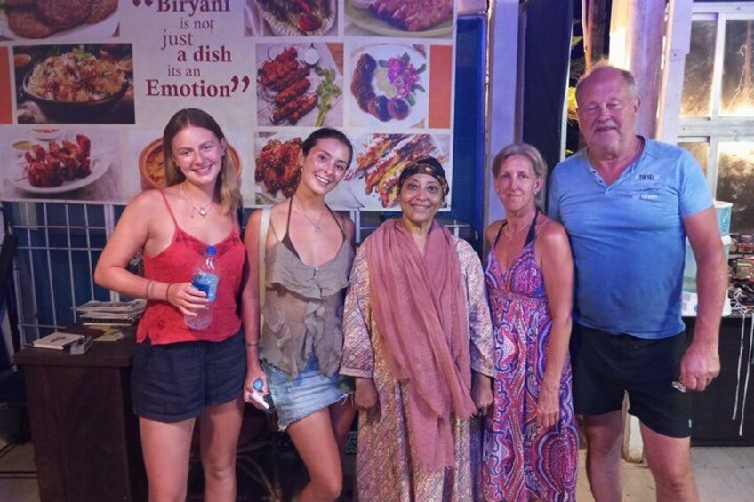 A group of people standing in a kitchen area with a sign that reads "Biryani is not just a dish, it's an Emotion". 3