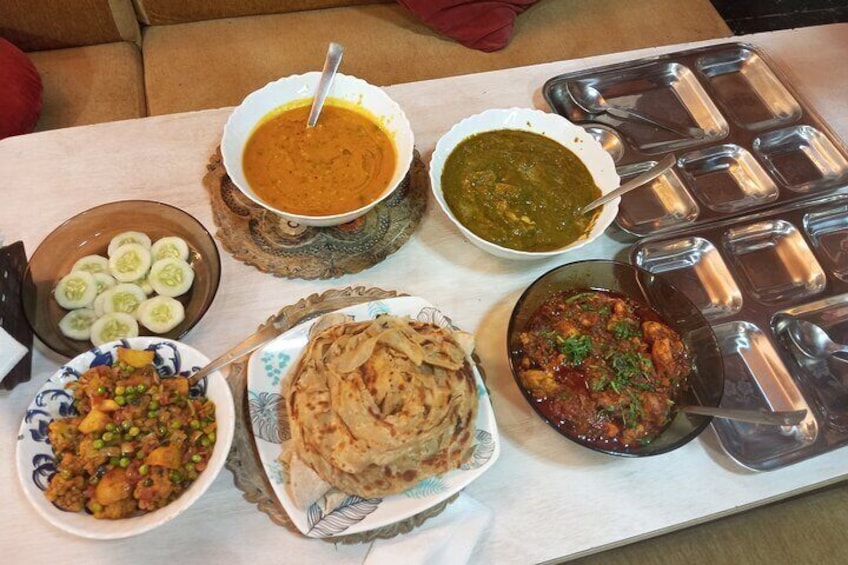Een tafel met diverse Indiase gerechten, zoals curry, rijst en naanbrood. 5