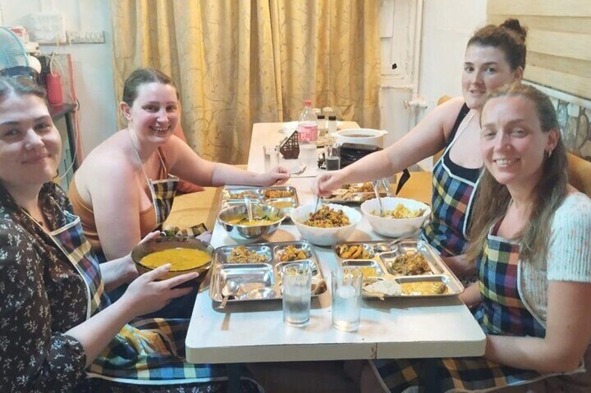 Vier personen zitten rond een tafel met verschillende gerechten. 3