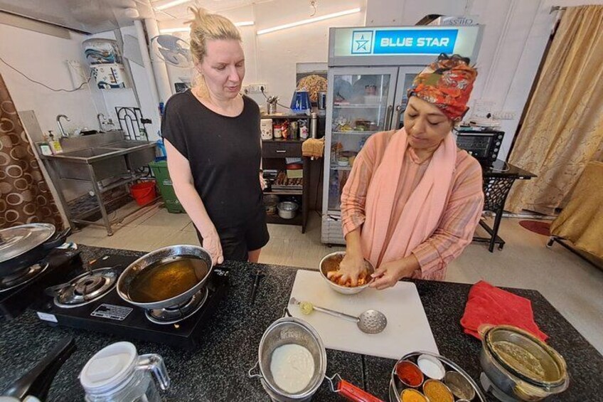 Two people cooking in a kitchen with various utensils and ingredients on the counter. 4