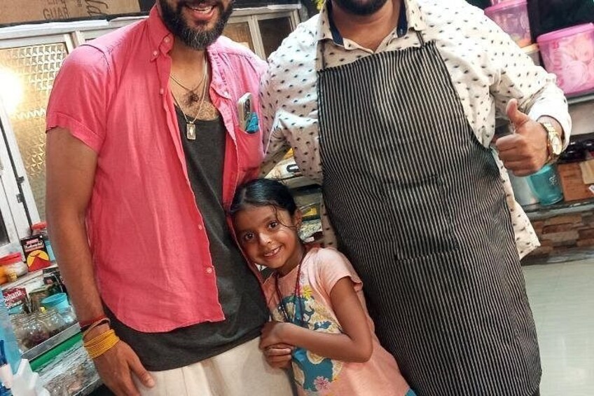 Three people in a market setting with shelves of goods in the background. 3