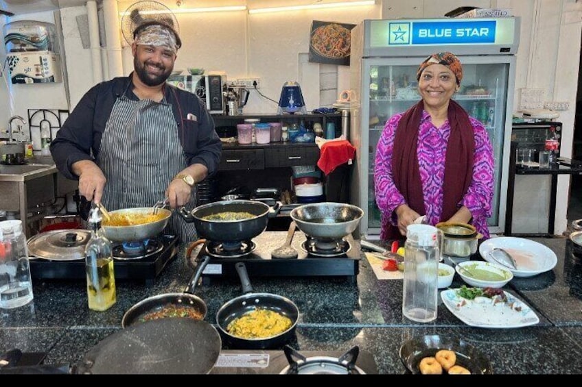 Twee personen koken in een keuken met verschillende pannen en potten op het aanrecht. 4