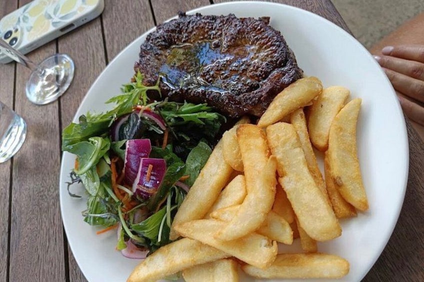 Un plato con un bistec, papas fritas y una ensalada. 3