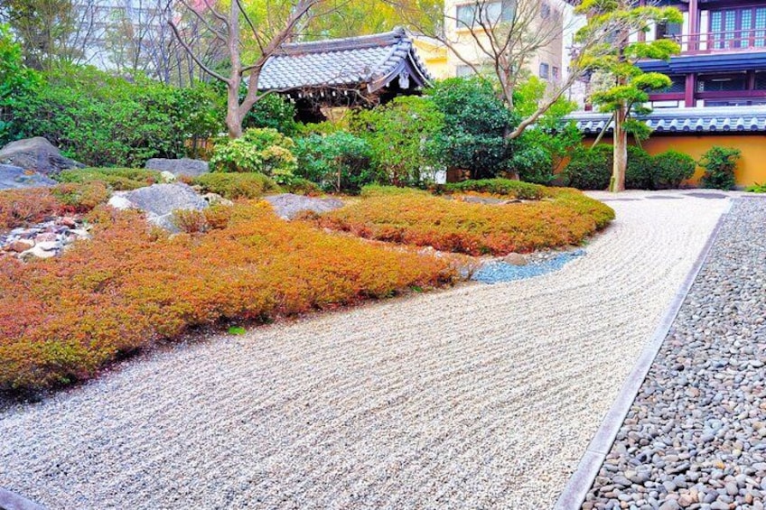 En traditionel japansk have med grussti, mosset vegetation, sten og en bygning med et tegltag. 4