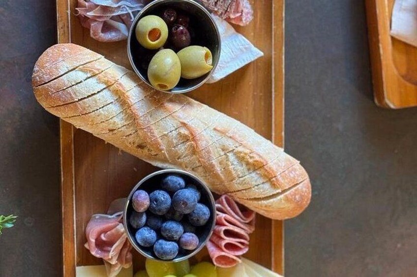 Een stokbrood, olijven en bosbessen op een houten plank. 5