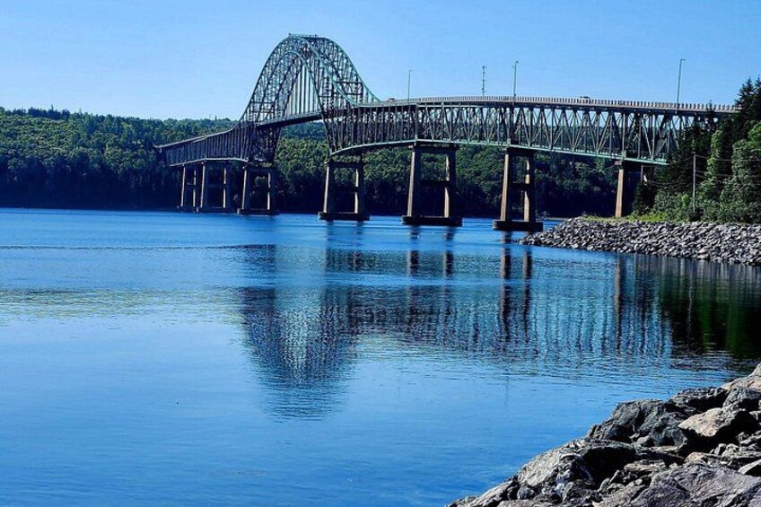 A large steel bridge over a calm lake with a forested shoreline. 4