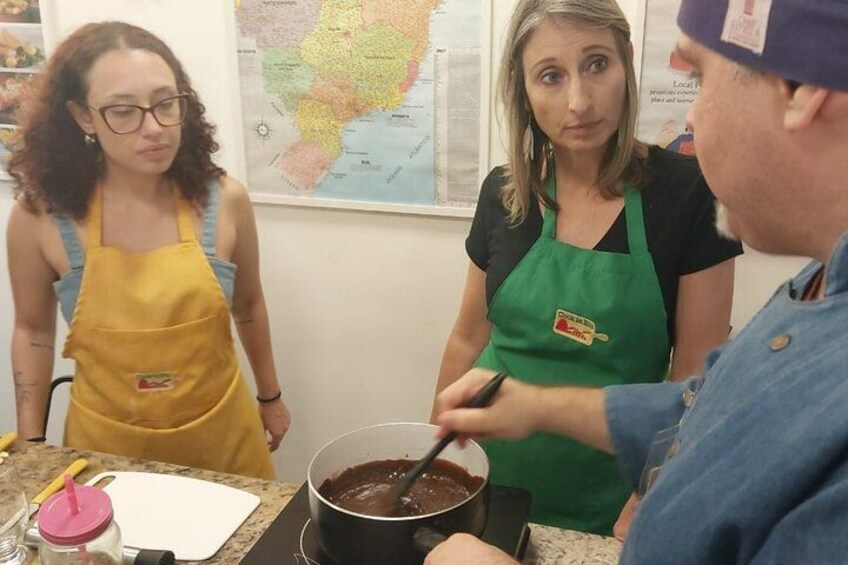 Trois personnes dans une cuisine, dont une qui remue le contenu d’une casserole. 2
