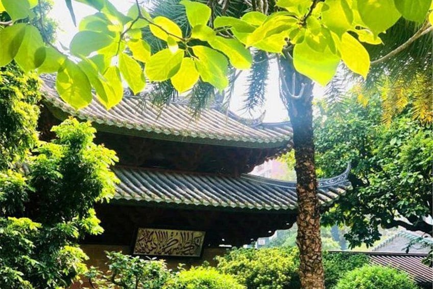 A traditional Japanese building with a tiled roof, surrounded by lush greenery and trees. 1