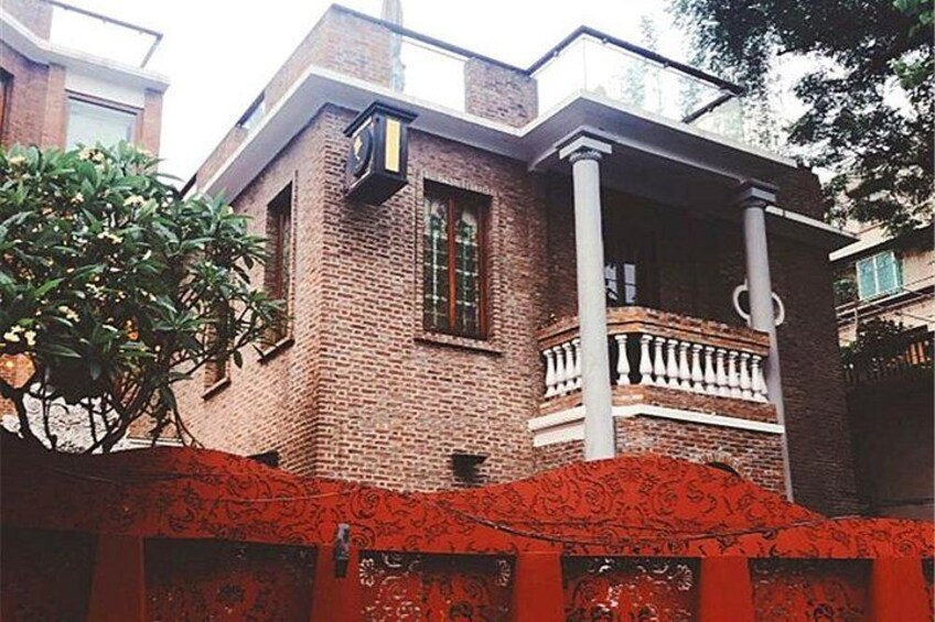 A brick building with a balcony, a tree, and a red fence. 4