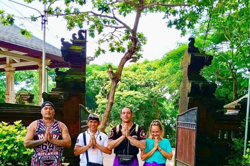 Un grupo de personas en un patio de templo con arquitectura tradicional, incluyendo una puerta de piedra y un árbol. 2