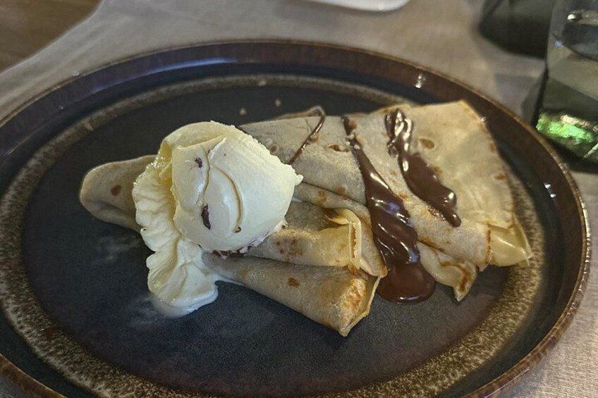 A plate of crepes with chocolate sauce and a scoop of vanilla ice cream. 2