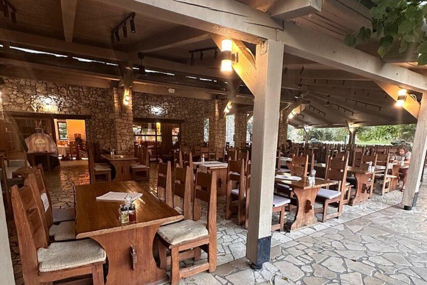 An outdoor restaurant with stone walls, wooden tables, and chairs. 5