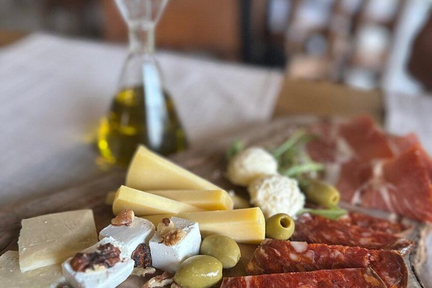 A charcuterie board with various cheeses, olives, nuts, and cured meats. 4