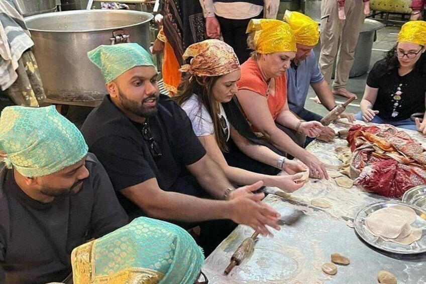 People preparing food, wearing head coverings, and using a rolling pin on a table. 5