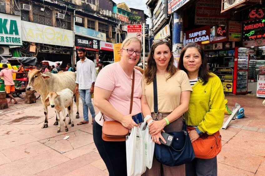 A street scene with people, a cow, and various shops. 1