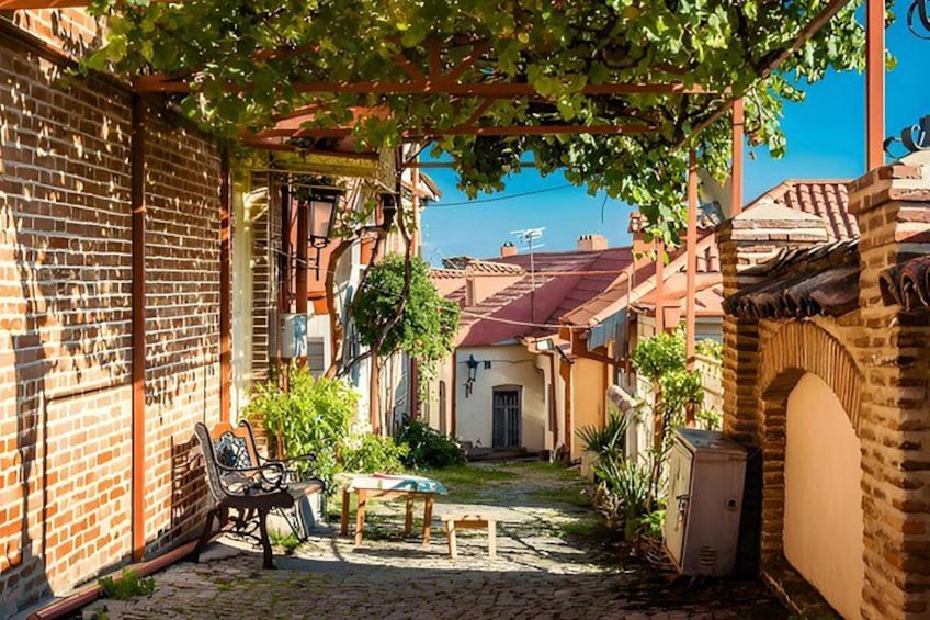 A cobblestone courtyard with a pergola, brick walls, and a small table. 3