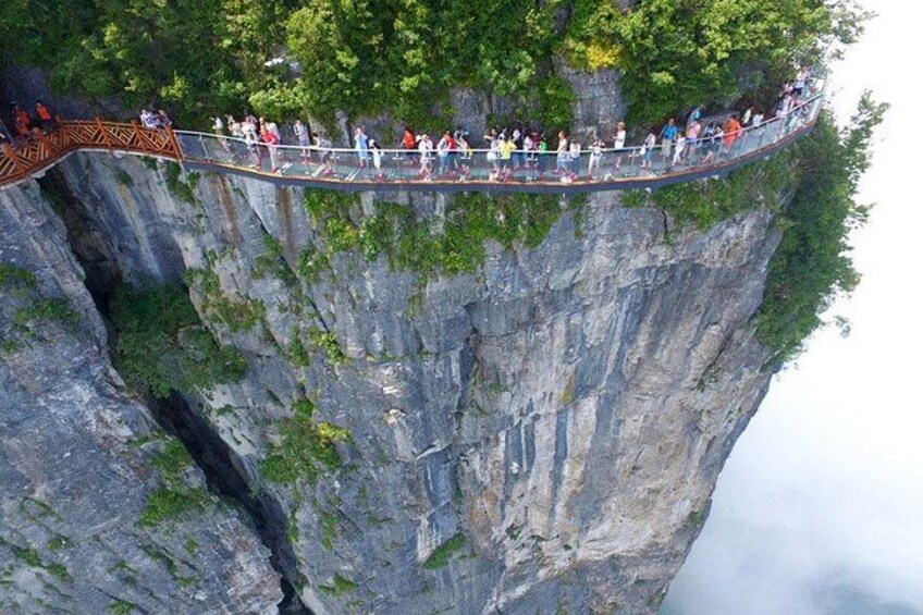 A suspension bridge over a steep cliff with people walking on it. 5