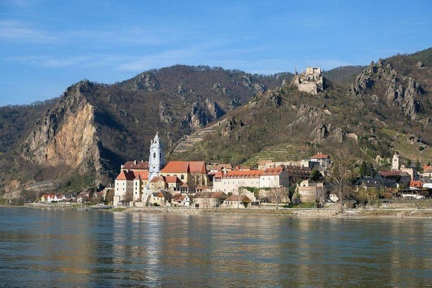 A historic town by a river with a prominent church and castle on a hill. 4