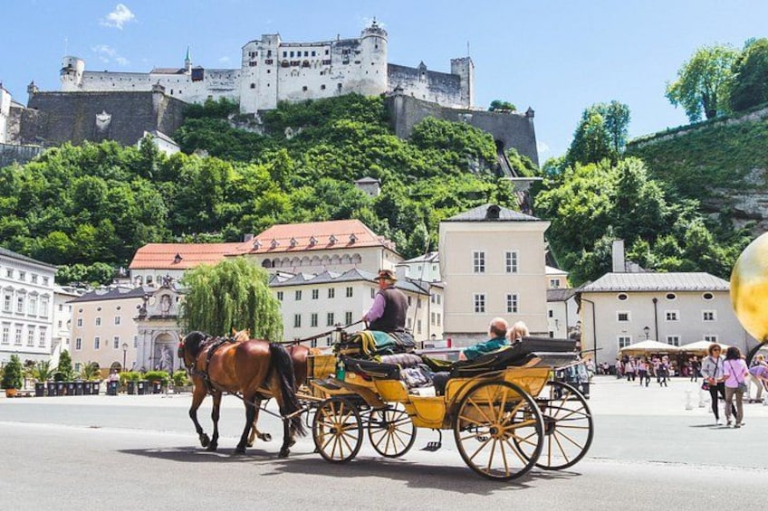 A horse-drawn carriage on a city street with a castle in the background. 3