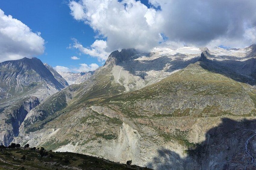 A mountainous landscape with rugged terrain and snow-capped peaks under a partly cloudy sky. 5