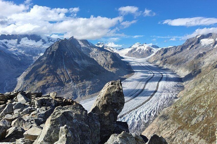 A glacier in a mountainous landscape with rocky terrain and snow-covered peaks. 2