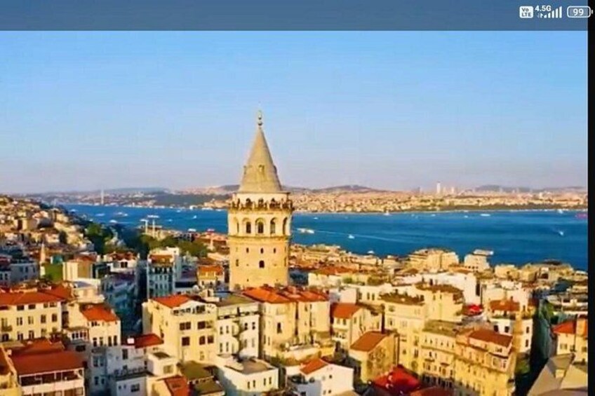 A coastal cityscape with a prominent tower, dense urban buildings, and a clear view of the sea. 4