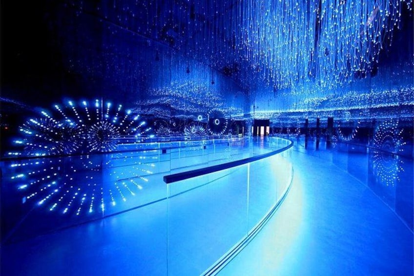 An indoor ice skating rink with blue lighting and a circular ice surface. 5