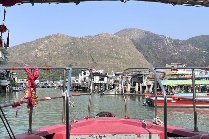 Un barco amarrado en un puerto con edificios y montañas al fondo. 1
