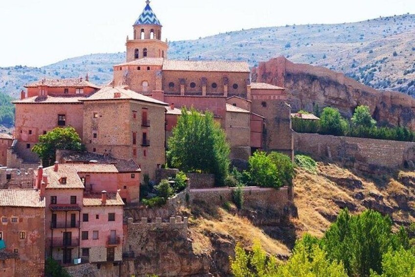 A historic town with a prominent tower, terraced buildings, and a hillside backdrop. 3