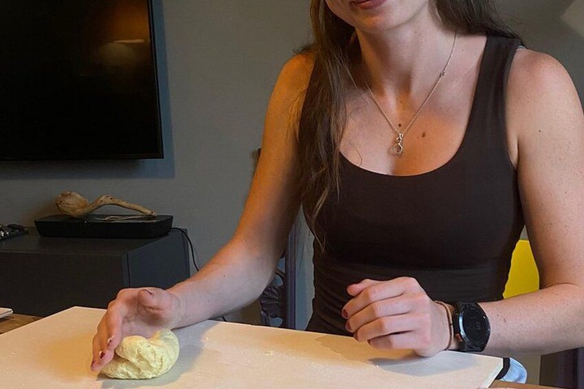 A person kneading dough on a white countertop. 3