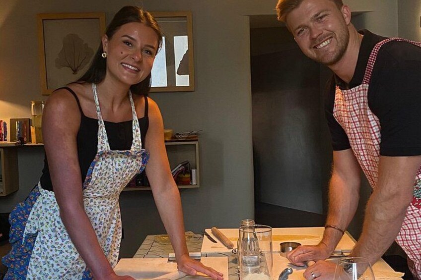 Two people in a kitchen with a table, a bottle, and a glass. 4