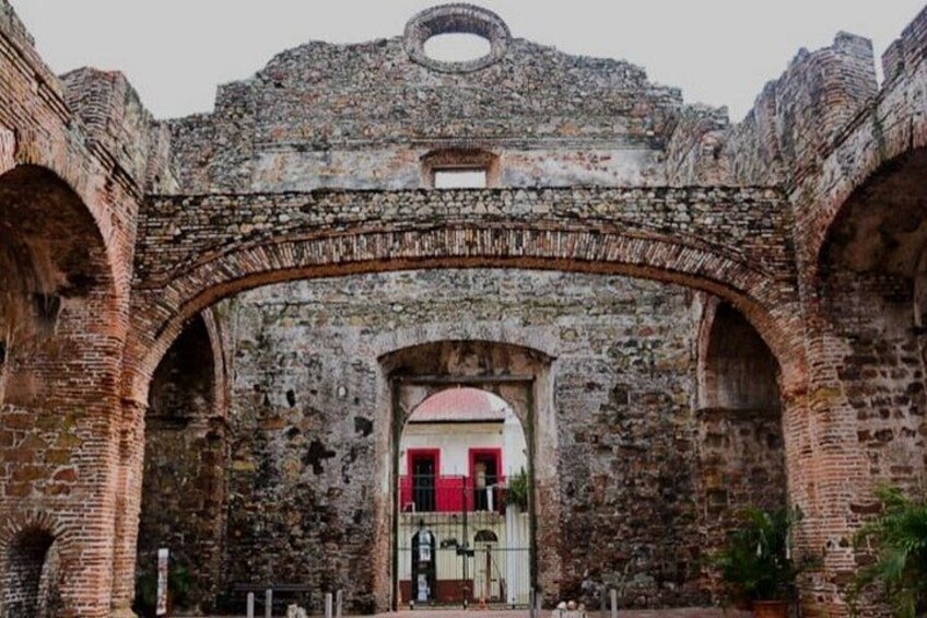 An ancient stone archway with a red door and a small window above it. 2