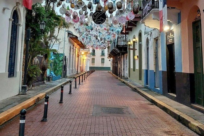 A street with a row of buildings, a brick pavement, and a series of hanging decorative plates. 5
