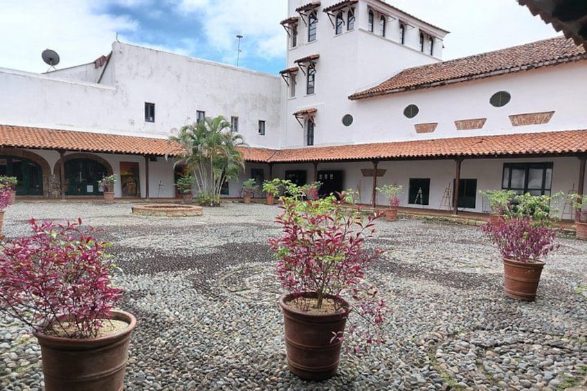 A courtyard with potted plants, a white building with a red-tiled roof, and a palm tree. 3