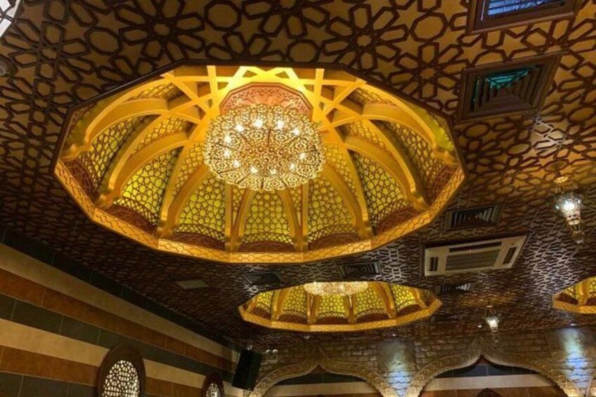 Un techo ornamentado con intrincados diseños geométricos y un candelabro central. 2